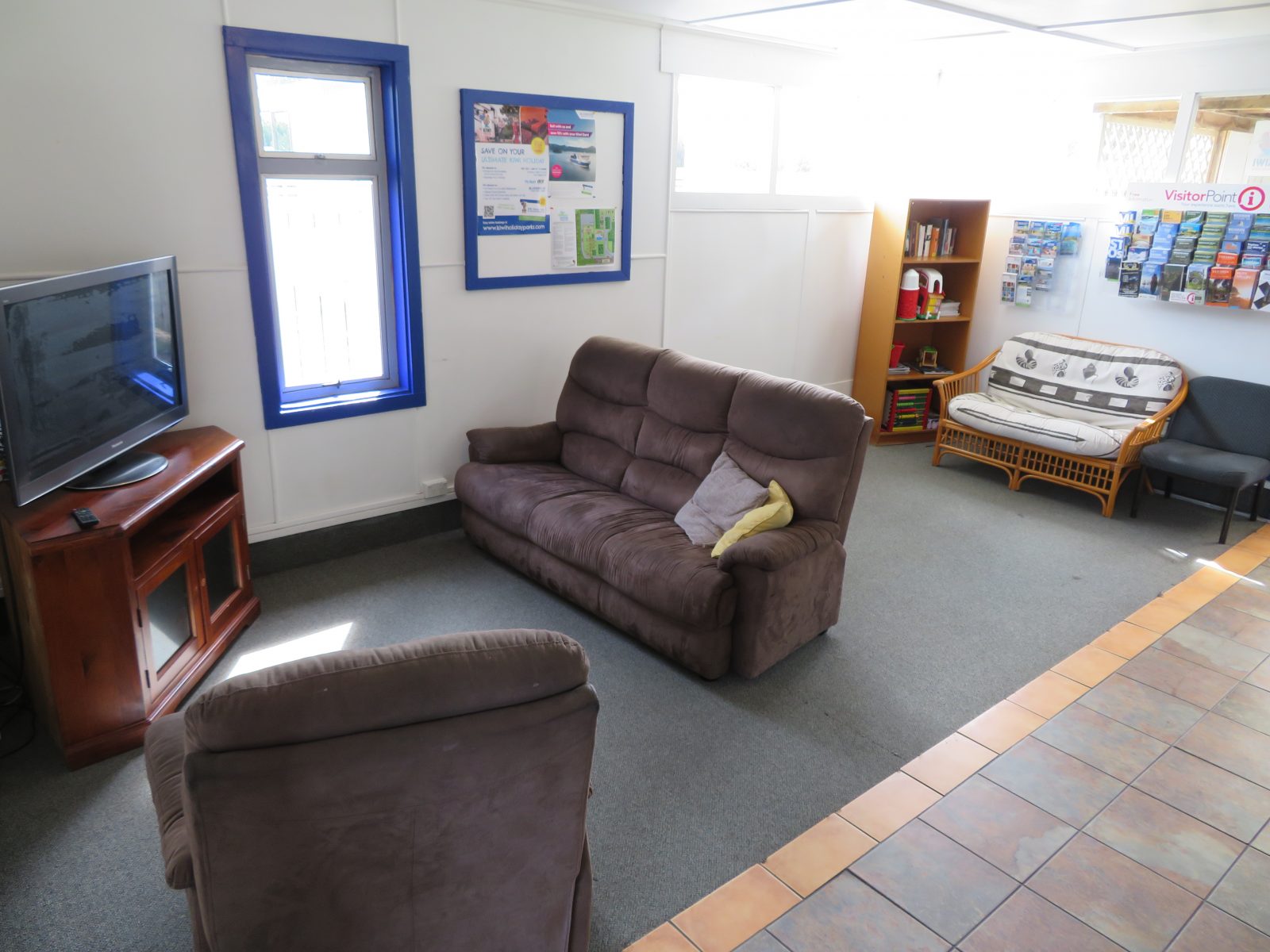 TV lounge with sofas, a television, bookshelf and a rack of visitor information brochures
