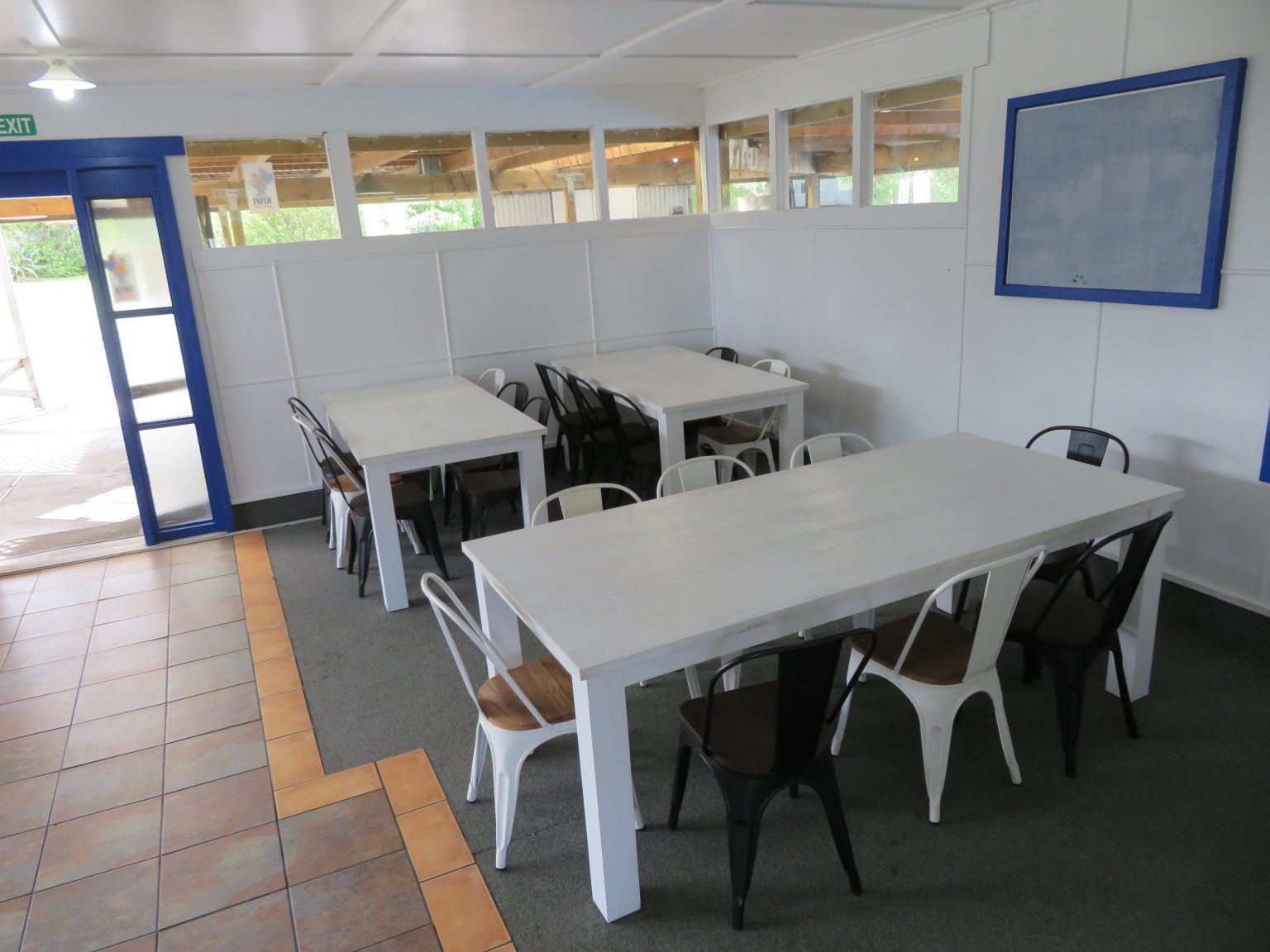 Indoor dining room with white tables and chairs beside a large window